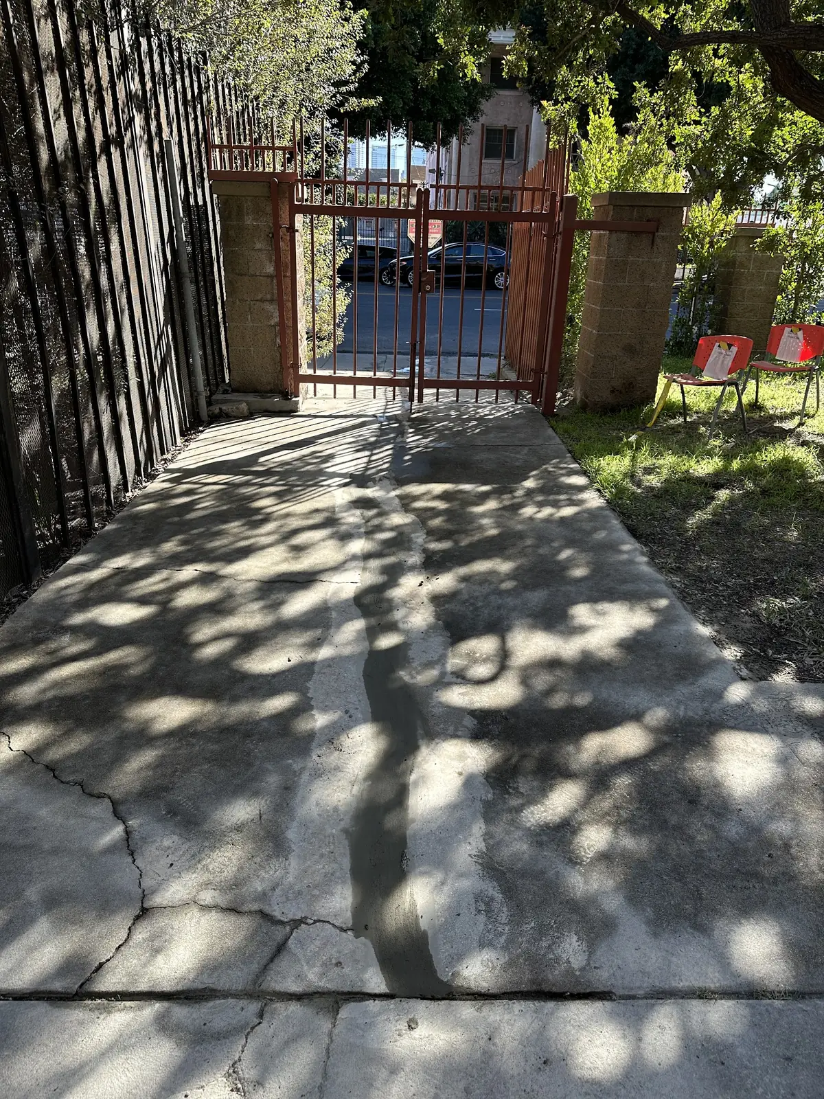 Cracked concrete walkway patched at a gated entrance